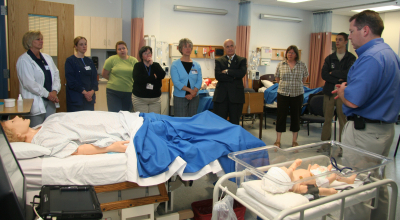 Photo from a neonatal demonstration in 2009. The photo depicts nursing students and faculty in front of a presenter as he demonstrates the neonatal simulator.