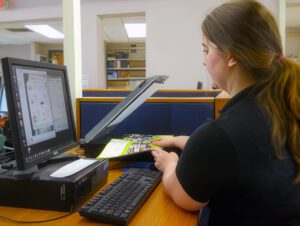 a female student makes use of a scanner in the library