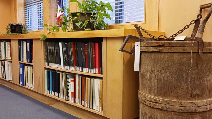 Bookshelves lined with books and agricultural artifacts nearby